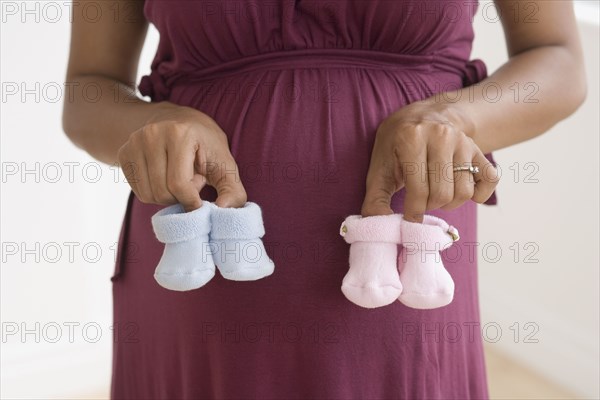 Pregnant African woman holding baby shoes