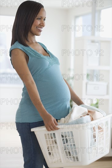 Pregnant African woman carrying laundry basket