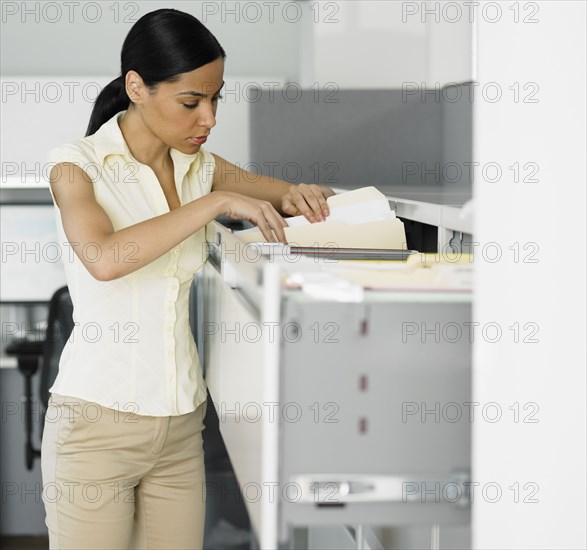 African businesswoman looking in file cabinet