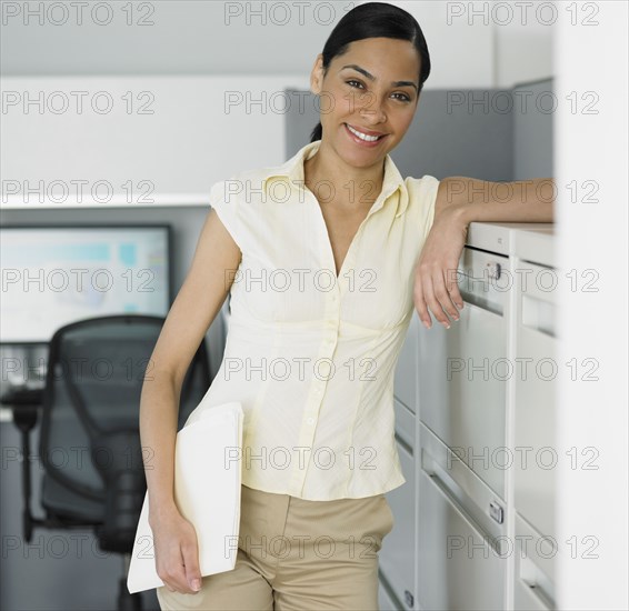 African businesswoman leaning against file cabinet