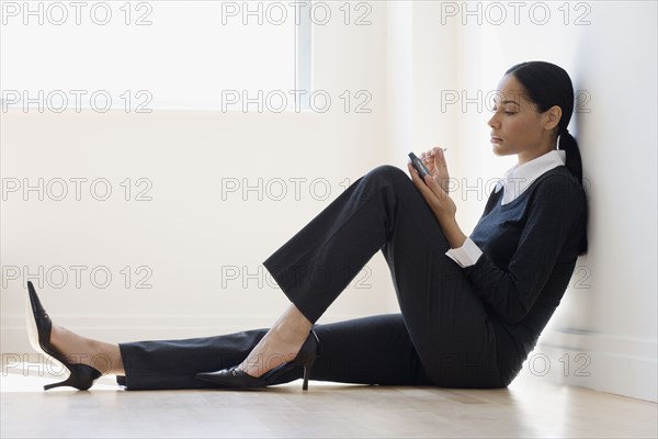 African businesswoman on floor using electronic organizer