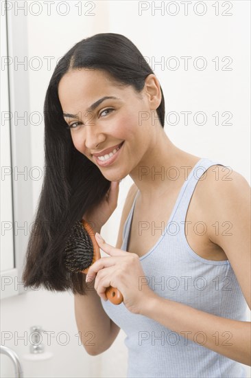 African woman brushing hair in bathroom