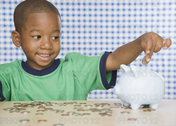 African boy putting change in piggy bank