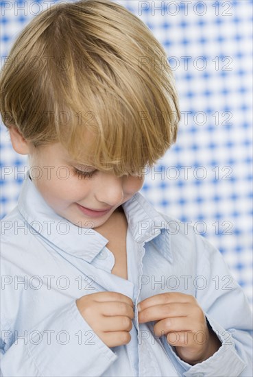 Young boy buttoning shirt