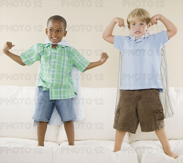 Two young boys wearing capes on sofa