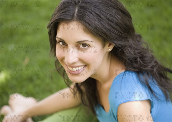 Portrait of Hispanic woman sitting in grass