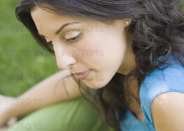 Portrait of Hispanic woman sitting in grass