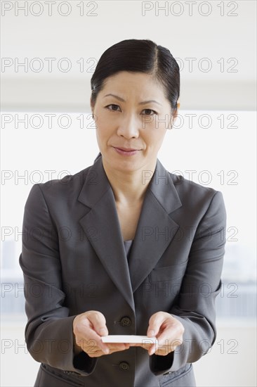 Middle-aged Asian businesswoman offering business card