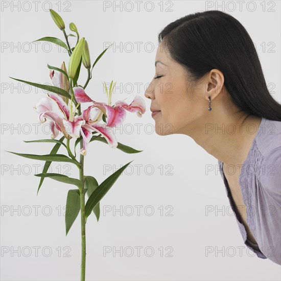 Profile of Asian woman smelling flowers