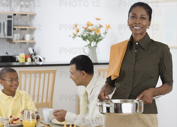 African woman serving breakfast to husband and son