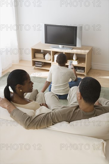 Rear view of African family watching television in livingroom