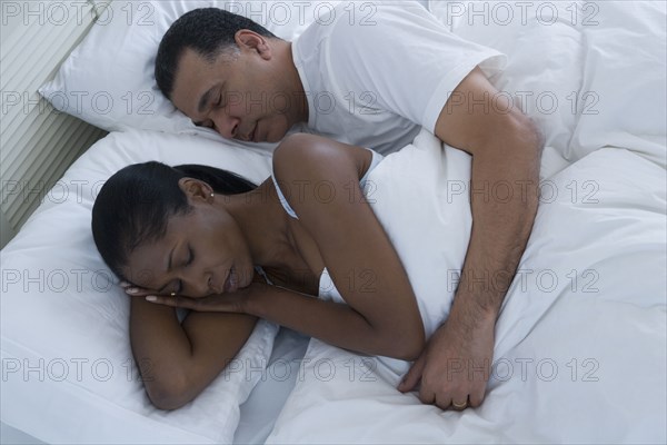 Middle-aged African couple sleeping in bed