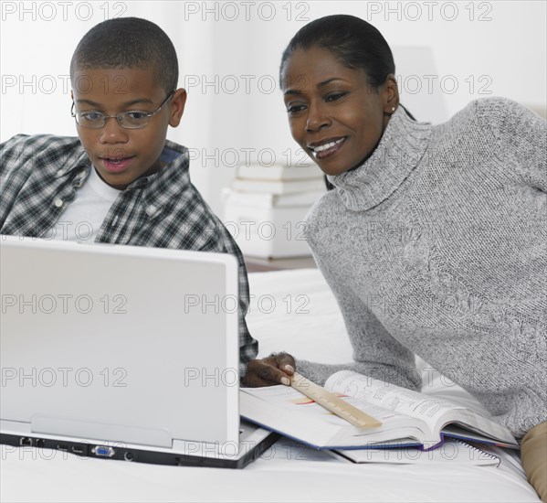 African mother helping son study with laptop