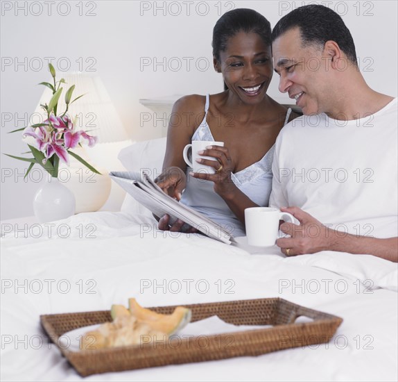 Middle-aged African couple having breakfast in bed