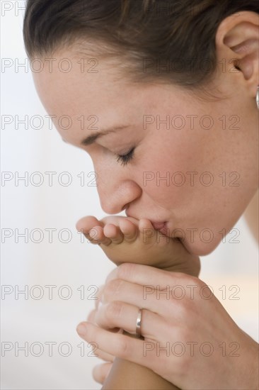 Hispanic mother kissing baby's foot