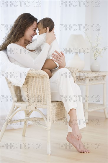 Hispanic mother sitting in chair hugging baby
