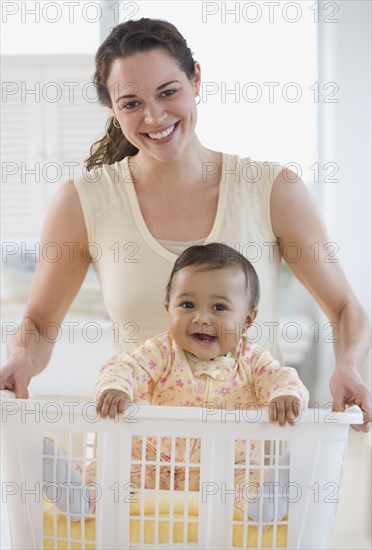 Hispanic mother carrying baby in laundry basket