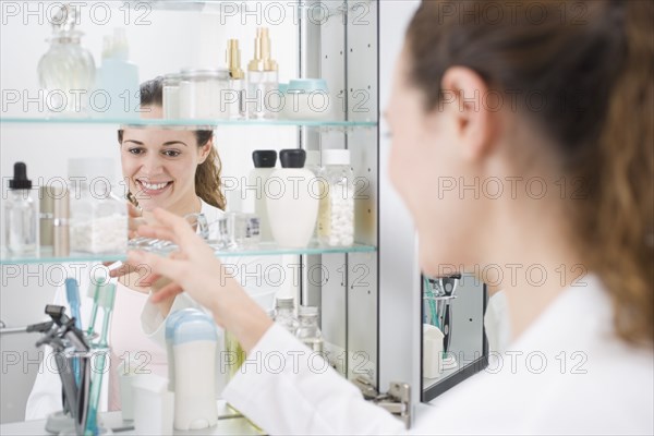 Hispanic woman reaching into medicine cabinet