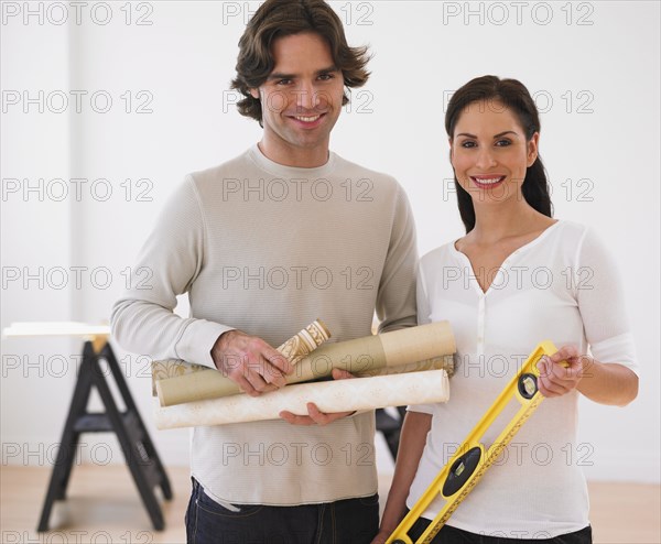 Hispanic couple holding rolls of wallpaper