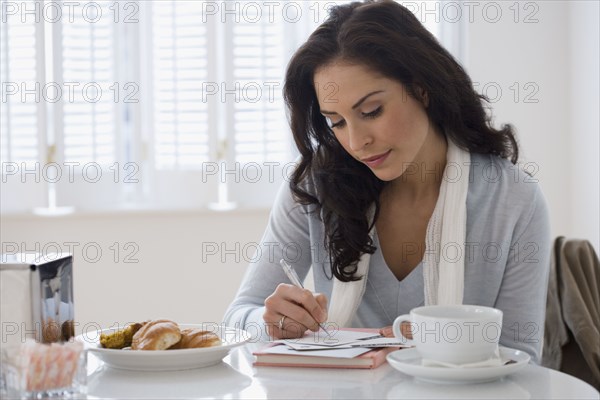 Hispanic woman writing letter in cafe