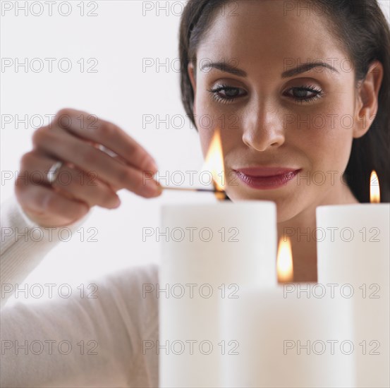 Close up of Hispanic woman lighting candles