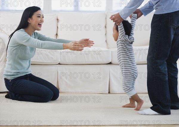 Asian parents helping baby walk