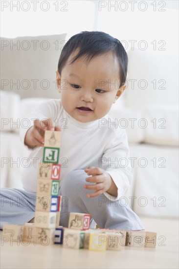 Asian baby playing with blocks on floor