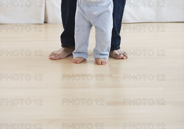 Low section of barefoot baby and father