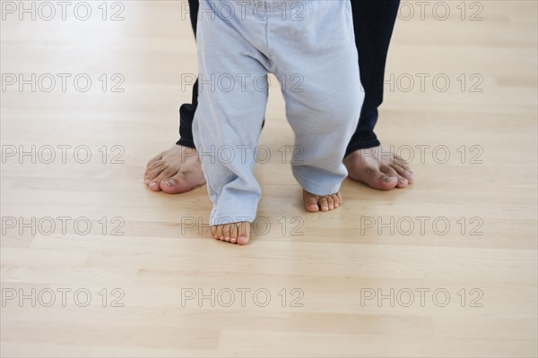 Low section of barefoot baby and father