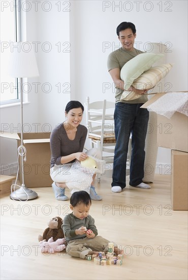 Asian parents watching baby play with blocks on floor