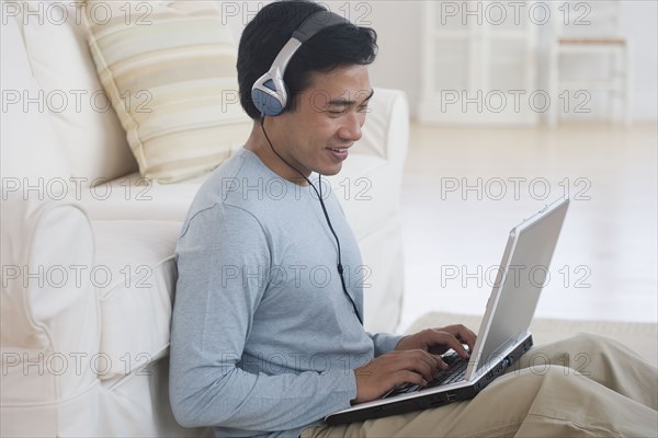 Asian man using laptop with headphones