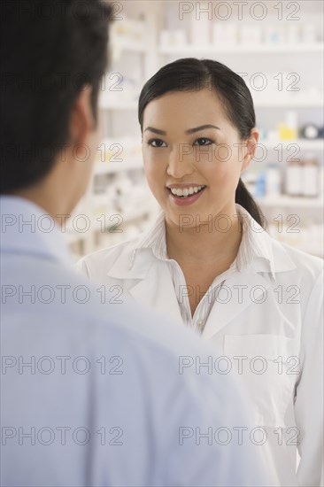 Asian female pharmacist talking to customer