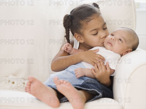 African girl kissing baby sibling