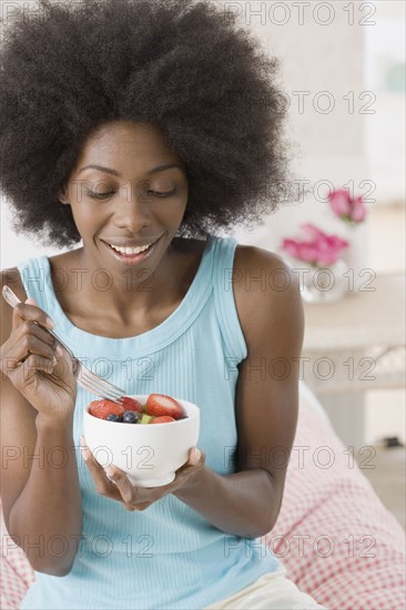 African woman eating bowl of fruit