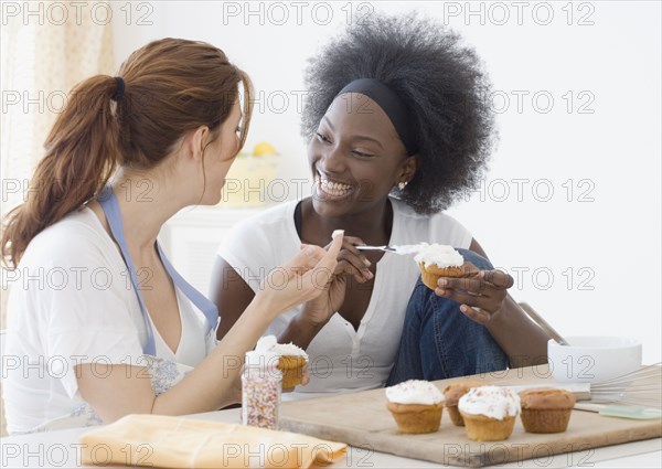 Two women icing cupcakes