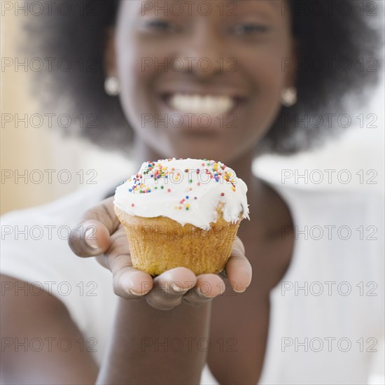 African woman holding cupcake