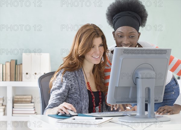 Two female college students using computer in classroom