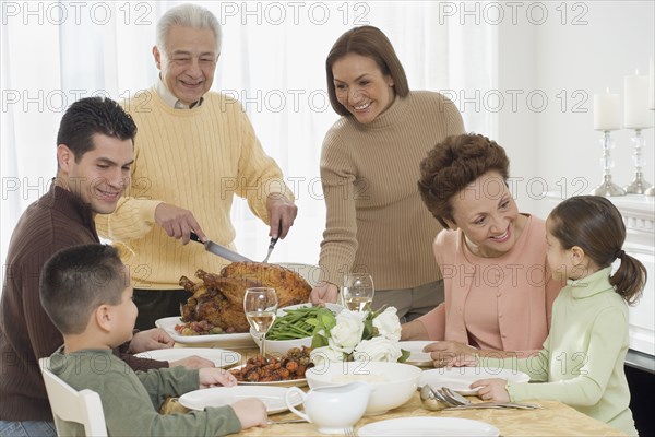Multi-generational Hispanic family eating at Thanksgiving table