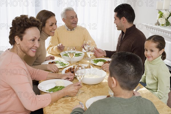 Multi-generational Hispanic family eating at Thanksgiving table