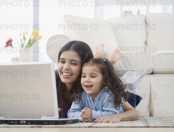 Hispanic mother and daughter looking at laptop