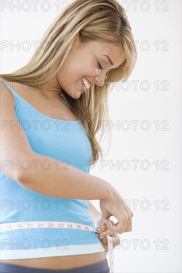 Hispanic woman measuring waist