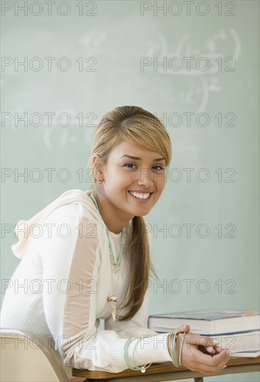 Young Hispanic woman sitting at school desk