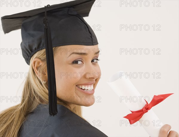 Young Hispanic woman wearing graduation cap and gown