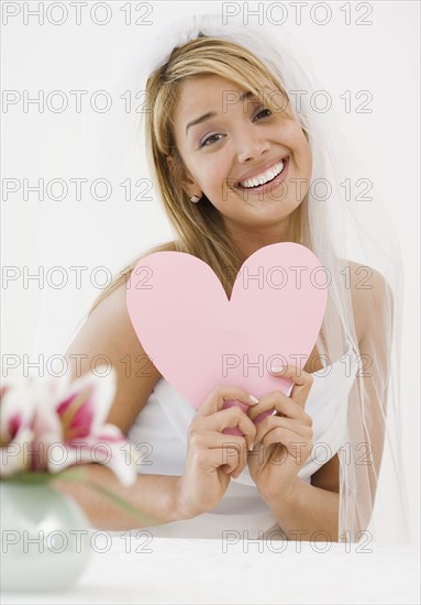 Hispanic bride holding paper cutout heart