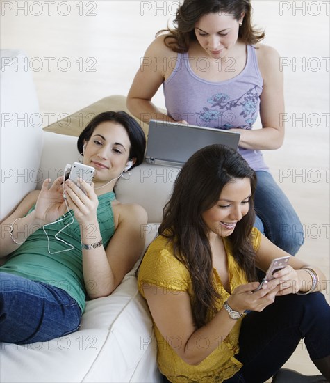 Three young women using wireless devices