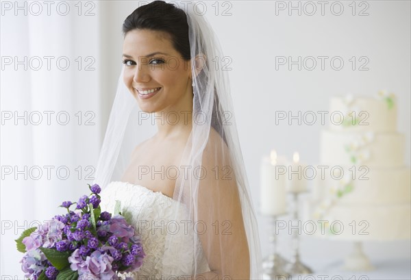 Hispanic bride holding bouquet of flowers