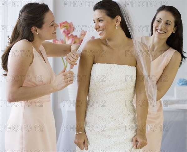 Hispanic bride having veil adjusted