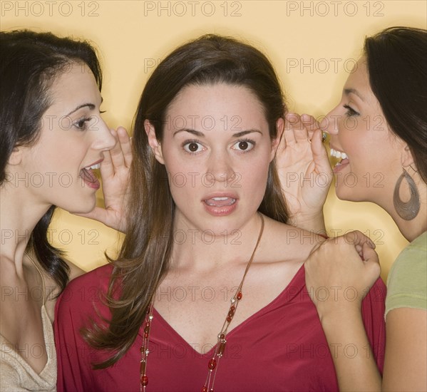 Women whispering secrets to friend