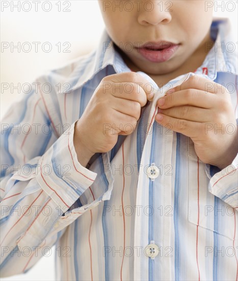 Hispanic boy buttoning shirt