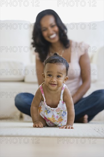 African American mother watching baby crawl